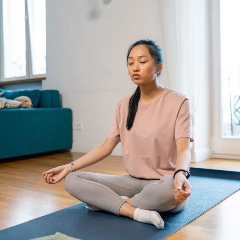 Young woman meditating indoors in a serene setting for relaxation.